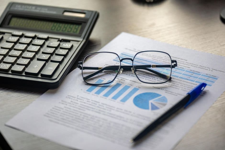 Financial document with a calculator, pen, and glasses symbolizing data analysis.