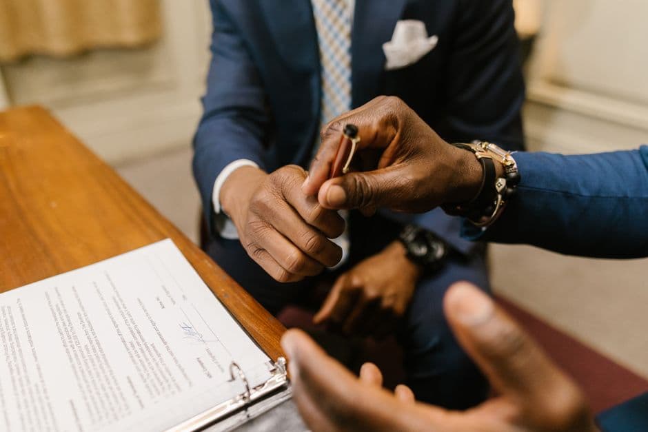 Two businessmen in suits finalize a contract, highlighting teamwork and agreement.